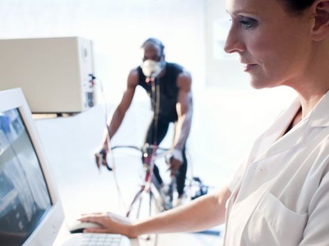 woman doctor monitoring value of a man cycling