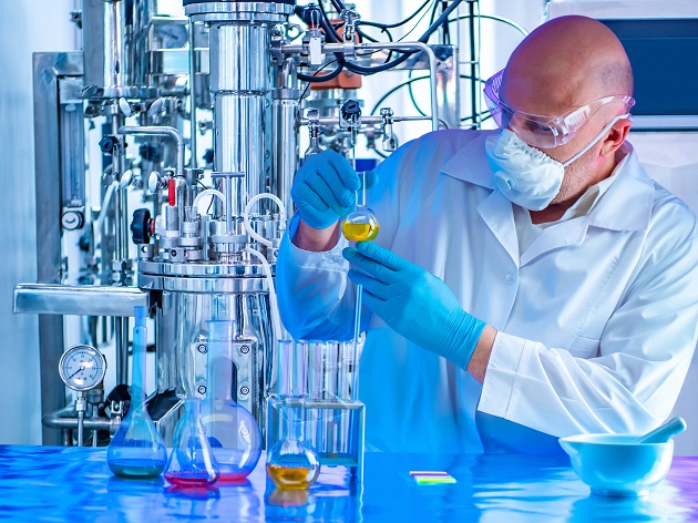 man with glasses and mask performing a Back-pressure regulation for catalyst research in the laboratory