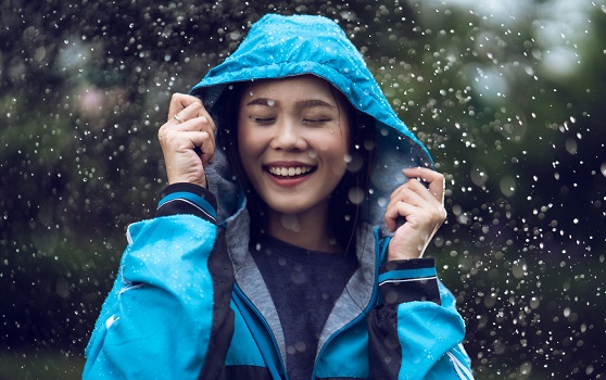 Smiling woman wearing a rain coat under the rain